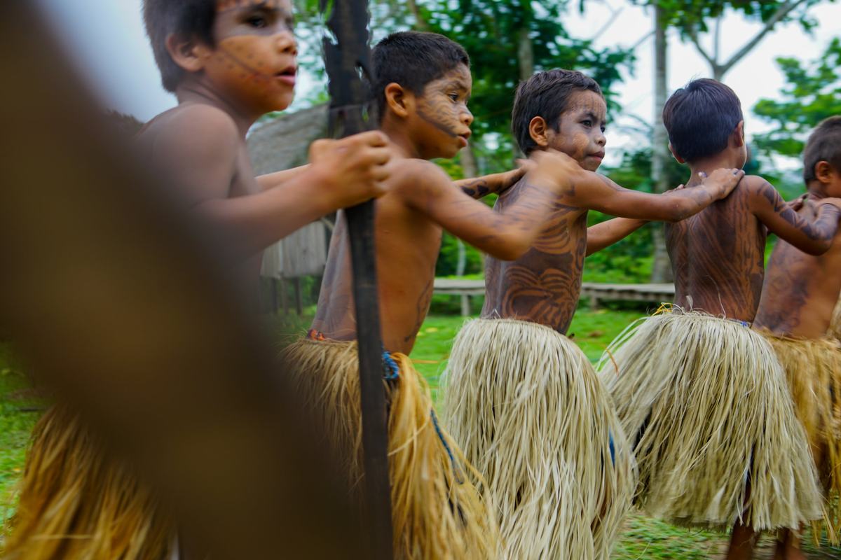Children with body paint and straw skirts dancing in a line