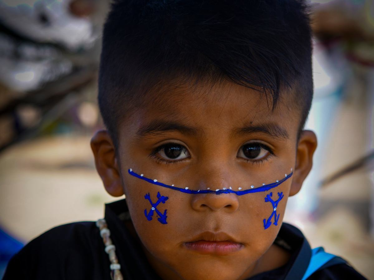 Portrait of a boy with blue face paint and a shell necklace
