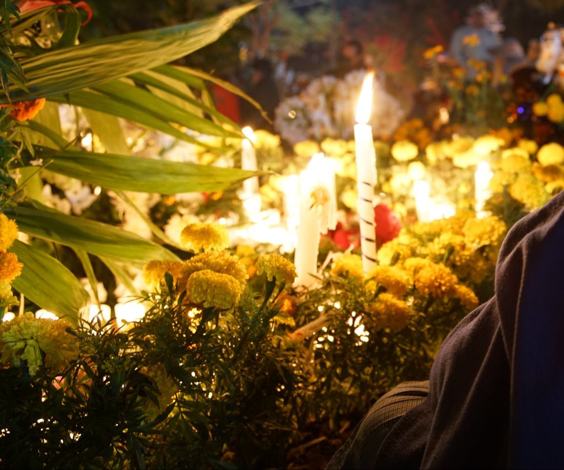 Marigolds and lit candles on a grave at night in Huautla